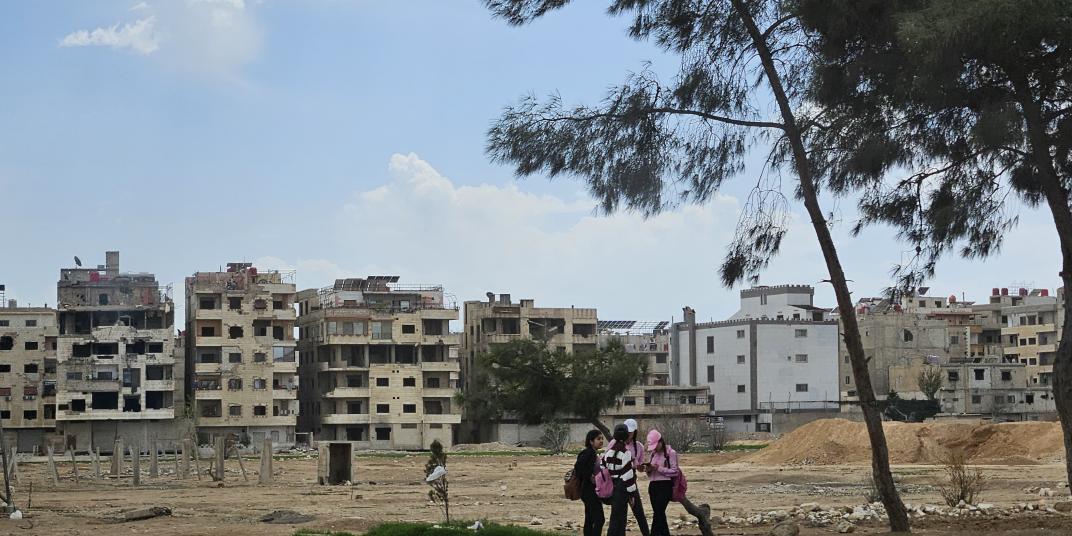 damaged houses in Damascus with people in front 