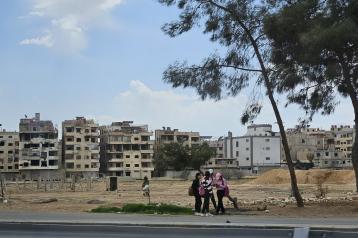 Landscape with destroyed houses and group of young people standing infant